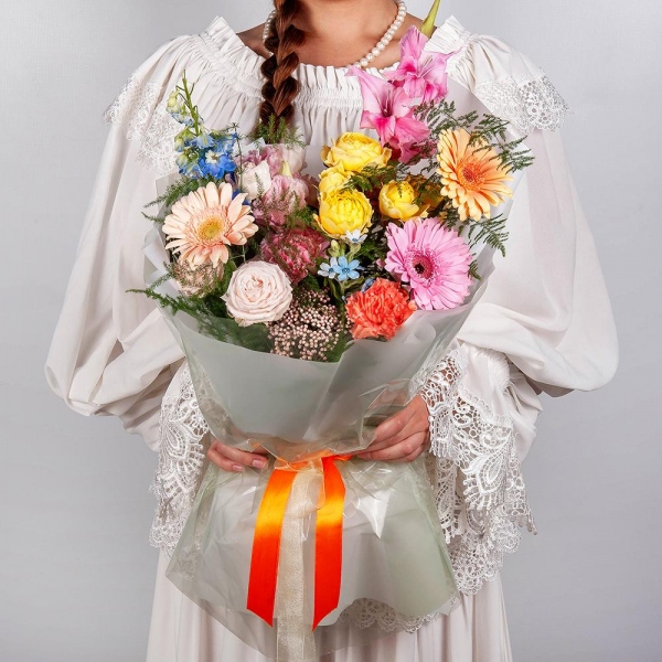 Gerbera daisies - 2, Pink Gladiolus - 1, Pink carnation - 5, Peony sprayrose - 1, Spray rose: yellow, orange 50 cm - 1, Gerbera pink - 3, Pink Lisianthus (Eustoma) - 1, Cream gerbera - 2, Blue Delphinium, Asparagus setaceus (1 pc.), Wrapping Paper