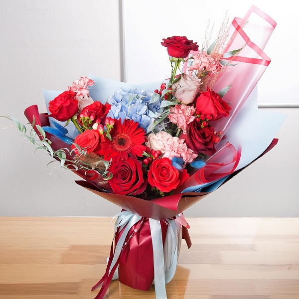 Gerbera red - 1, Blue/purple hydrangea - 1, Pink carnation - 4, Red rose 50 cm - 8, Rose Cream 50 cm - 3, Hypericum, Ruscus italian, Dried flowers in assortment, Wrapping Paper