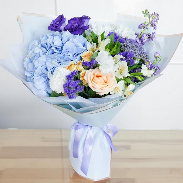 Matthiola Lilac - 2, Rose Cream 50 cm - 3, Carnation white, cream - 3, Spray rose: white, cream, light pink 50 cm - 2, Blue/purple hydrangea - 1, Alstromeria white, soft pink - 3, Baltica White Spray Chrysanthemum - 2, Purple Lisianthus (Eustoma) - 1, Trachelium, Blue Statice, Wrapping Paper