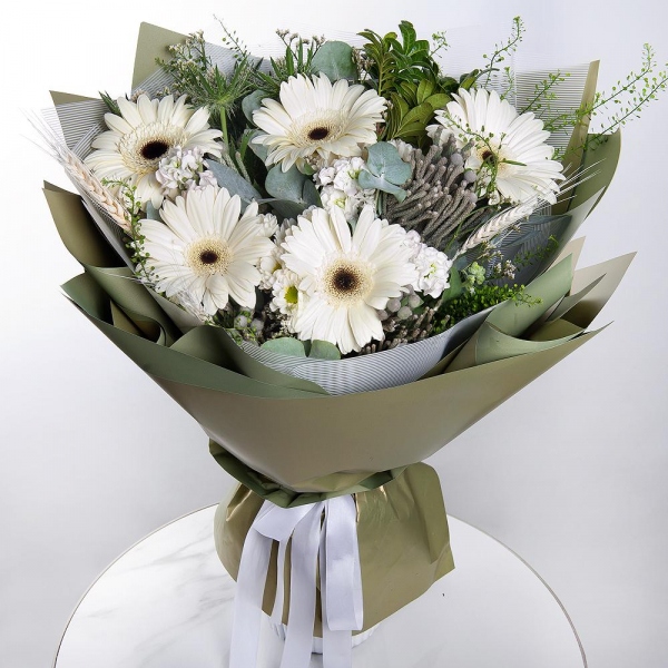 Gerbera white - 7, White Matthiola - 3, Pistachio, Eucalyptus, Brunia Green Lanuginosa (1 pc.), Eryngium, Green bell (1 pc.), Dried flowers in assortment, Wrapping Paper